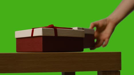 Nahaufnahme-Eines-Mannes,-Der-Verpackte-Geschenke-Vom-Tisch-Aufhebt,-Aufgenommen-Vor-Einem-Greenscreen